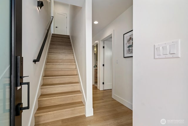 stairs with recessed lighting, wood finished floors, and baseboards