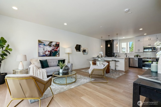 living area featuring light wood-style floors, baseboards, and recessed lighting