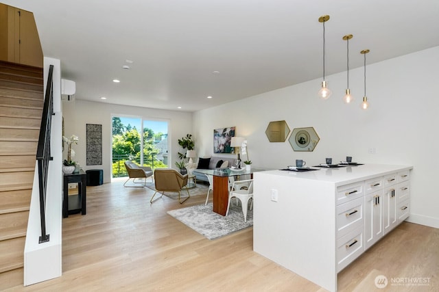 kitchen featuring light wood-style flooring, recessed lighting, white cabinets, light countertops, and pendant lighting