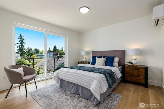 bedroom with light wood-type flooring, access to exterior, baseboards, and an AC wall unit