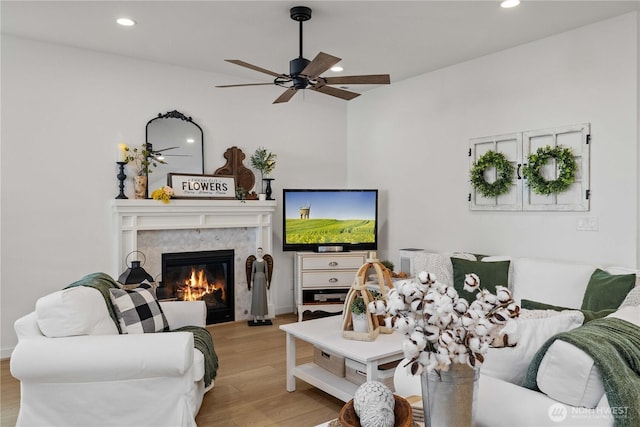 living area featuring a ceiling fan, recessed lighting, a fireplace, and wood finished floors