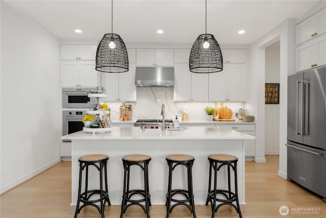 kitchen featuring appliances with stainless steel finishes, a kitchen bar, a sink, and under cabinet range hood