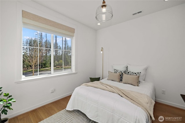 bedroom with baseboards, visible vents, wood finished floors, and recessed lighting