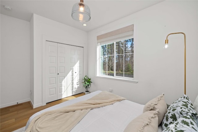 bedroom with recessed lighting, a closet, baseboards, and wood finished floors