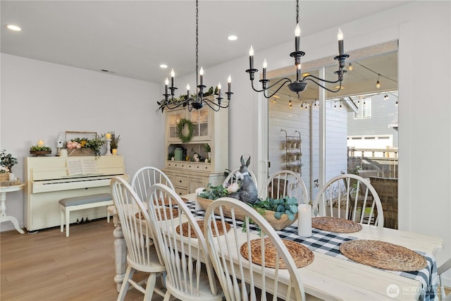 dining area with recessed lighting, wood finished floors, and an inviting chandelier