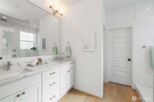 full bath featuring a sink, wood finished floors, walk in shower, and visible vents