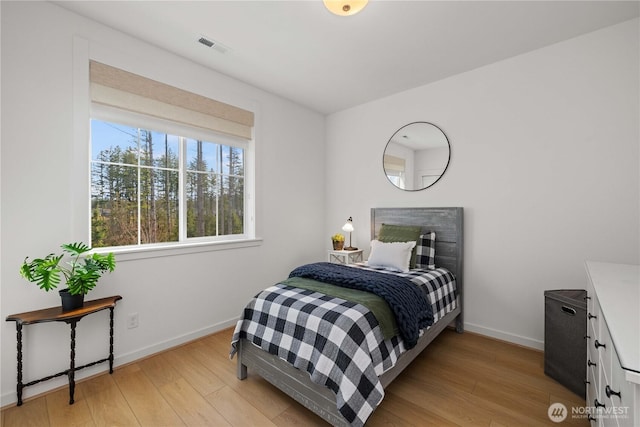 bedroom featuring light wood finished floors, visible vents, and baseboards