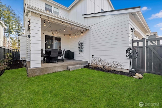 rear view of property featuring a yard, board and batten siding, a patio area, and a fenced backyard