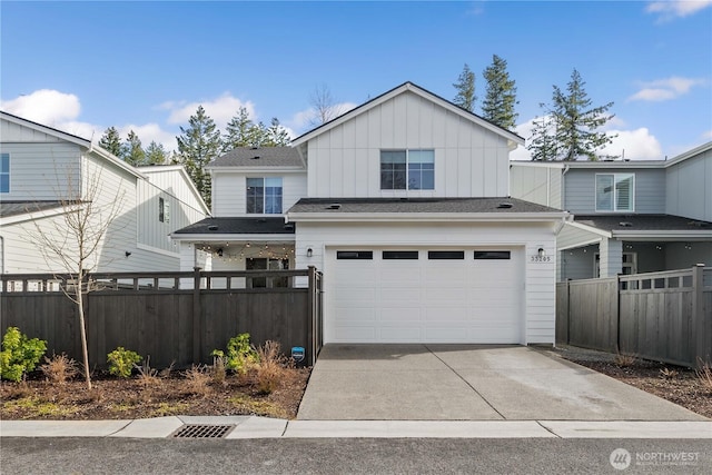 view of front facade featuring a garage, driveway, board and batten siding, and fence