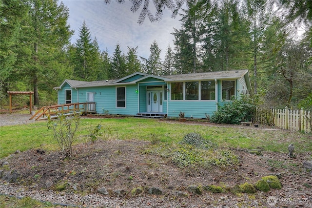 view of front of property with a sunroom, a front yard, and fence