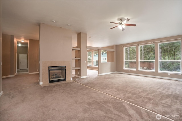 unfurnished living room featuring baseboards, a fireplace with flush hearth, a ceiling fan, and carpet flooring