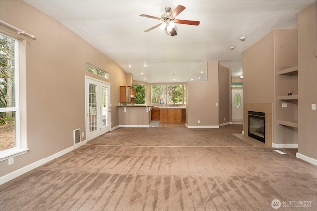 unfurnished living room with built in features, light colored carpet, and a fireplace