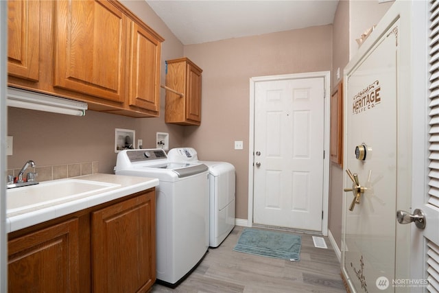 laundry area with visible vents, a sink, cabinet space, light wood-style floors, and separate washer and dryer