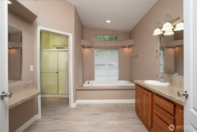 bathroom with vaulted ceiling, a bath, wood finished floors, and a shower stall