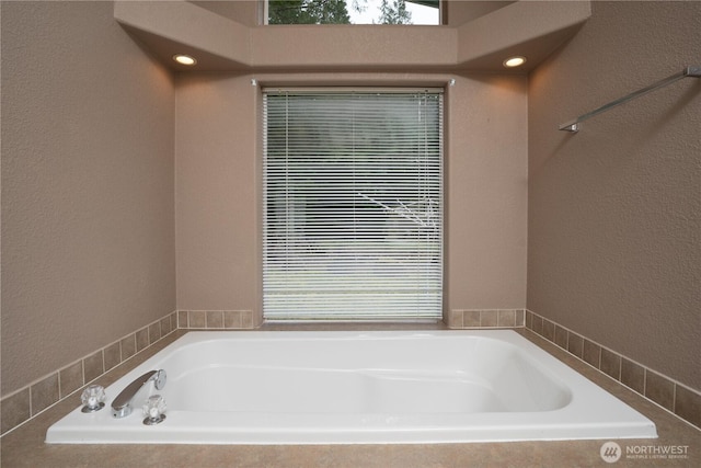 full bathroom with a garden tub and a textured wall