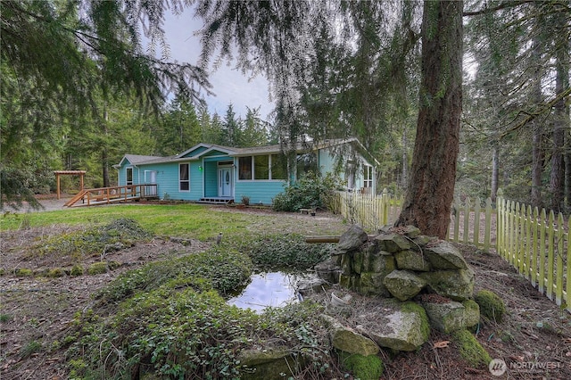 view of front facade featuring a deck, a front lawn, and fence