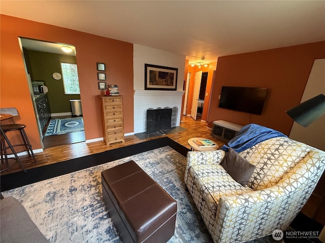 living room with a fireplace, baseboards, and wood finished floors