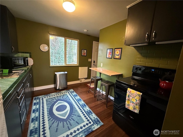 kitchen featuring black appliances, baseboards, dark wood-style floors, and tile counters