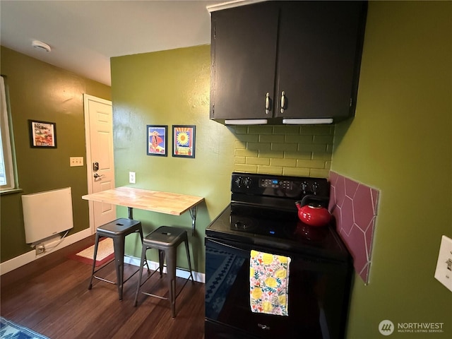 kitchen with baseboards, dark wood finished floors, radiator heating unit, black range with electric cooktop, and backsplash