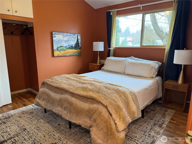 bedroom featuring a closet, wood finished floors, and baseboards