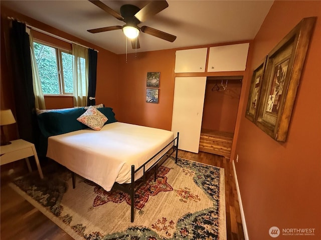 bedroom featuring dark wood-type flooring, a closet, and a ceiling fan