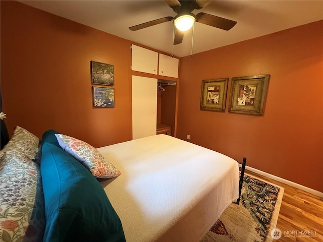 bedroom featuring ceiling fan, a closet, baseboards, and wood finished floors