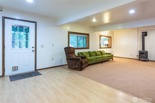 living area with a wood stove, light wood-style flooring, baseboards, and recessed lighting