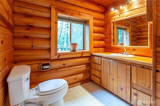 bathroom featuring toilet, rustic walls, vanity, and tile patterned floors