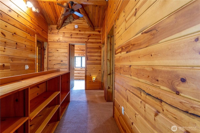 hallway featuring lofted ceiling, wooden walls, and carpet flooring