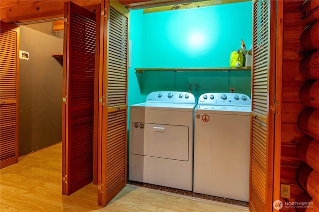 laundry area featuring laundry area, log walls, washing machine and clothes dryer, and wood finished floors