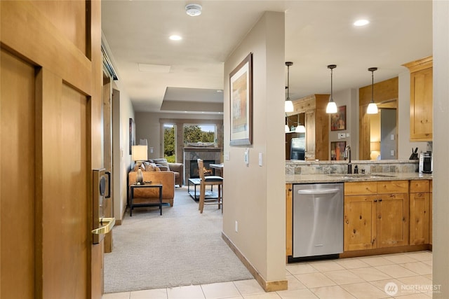 kitchen with light colored carpet, a sink, hanging light fixtures, dishwasher, and a glass covered fireplace