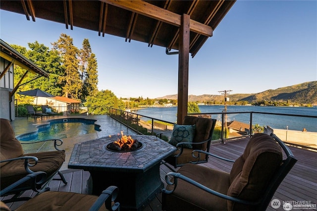 balcony with an outdoor fire pit and a water and mountain view