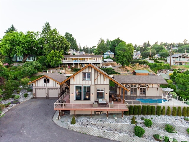 rear view of property featuring driveway, a garage, fence, a wooden deck, and board and batten siding