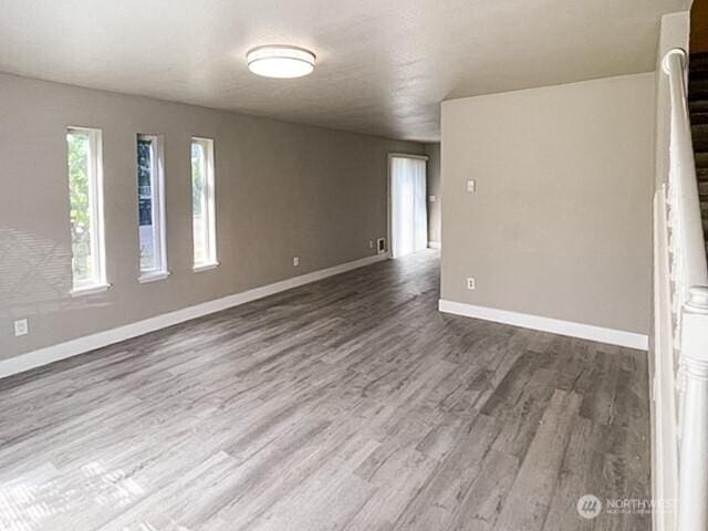 empty room featuring stairway, wood finished floors, and baseboards