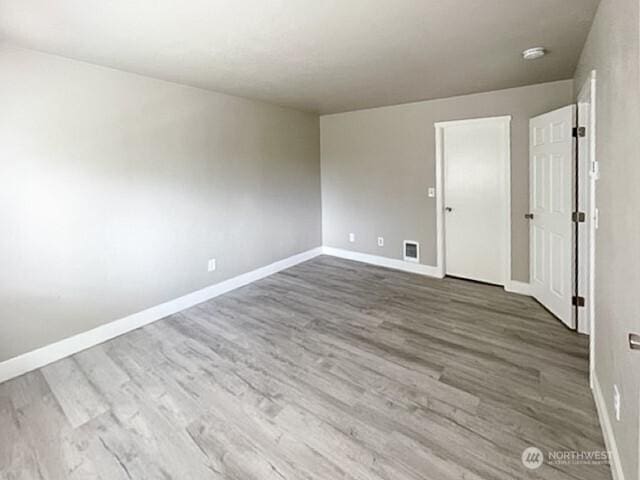 unfurnished bedroom with visible vents, baseboards, and wood finished floors