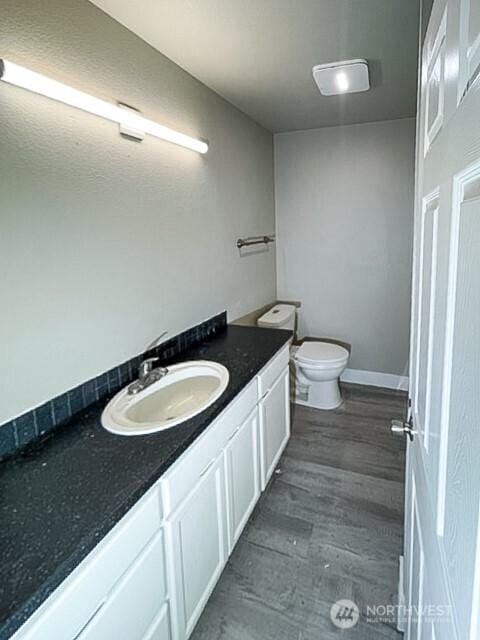 bathroom featuring toilet, wood finished floors, vanity, and baseboards