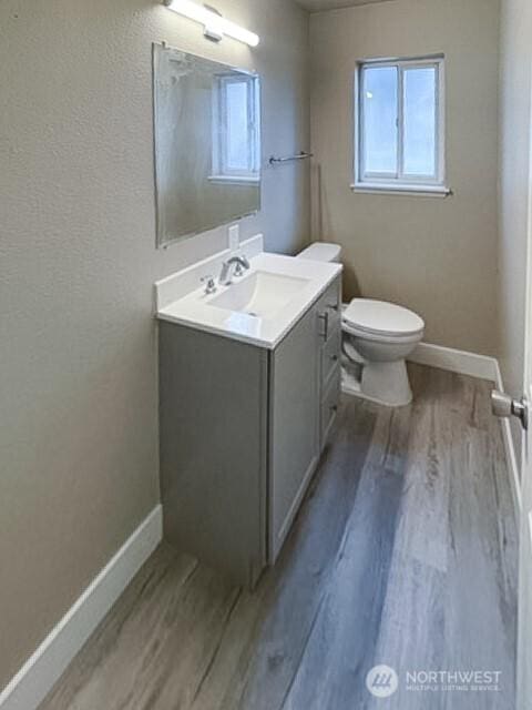 bathroom with baseboards, vanity, toilet, and wood finished floors