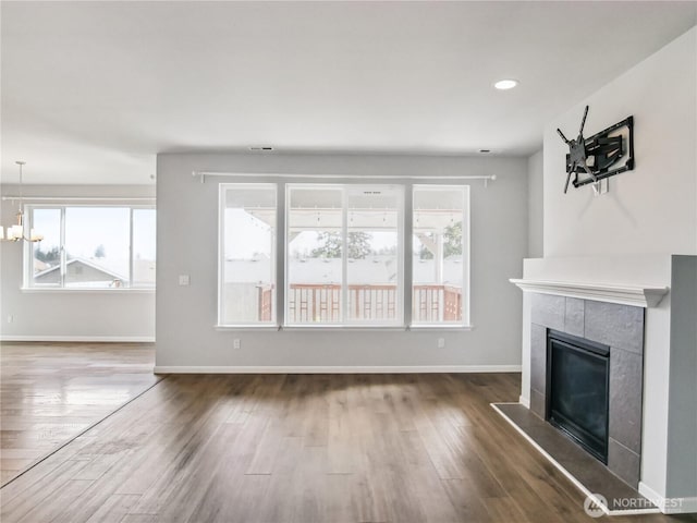 unfurnished living room with a tiled fireplace, recessed lighting, wood finished floors, and baseboards