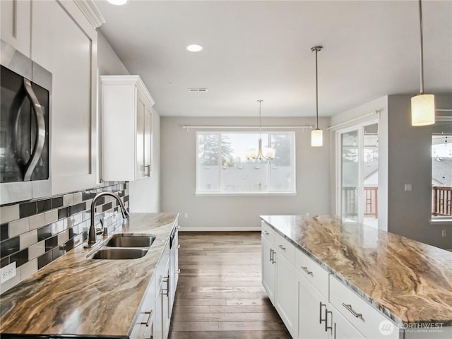 kitchen featuring dark wood-style floors, light stone countertops, a sink, white cabinetry, and tasteful backsplash