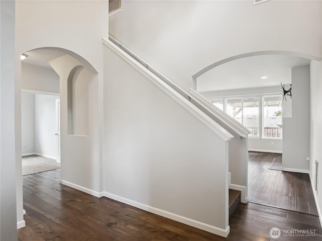 stairway with baseboards, arched walkways, and hardwood / wood-style flooring