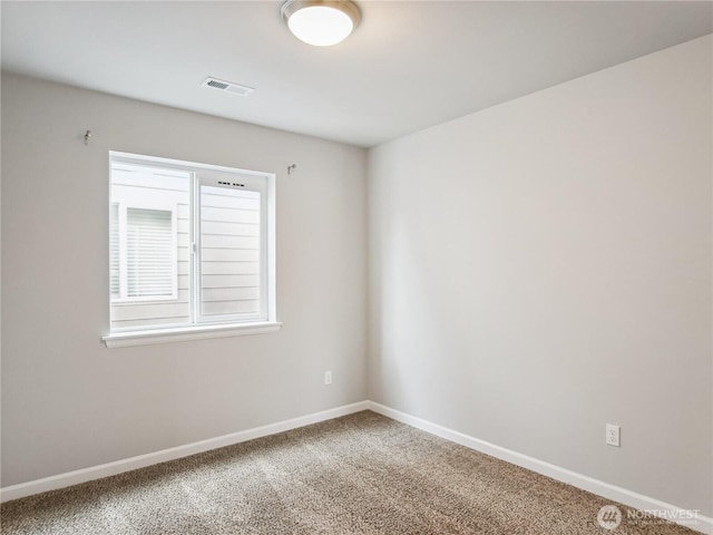 carpeted spare room with visible vents and baseboards