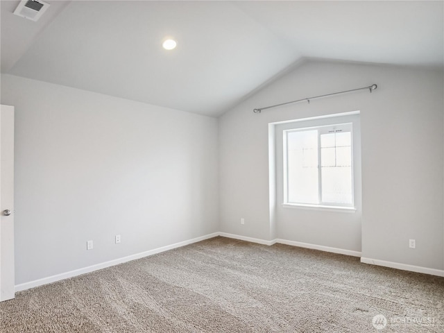 empty room with vaulted ceiling, carpet flooring, baseboards, and visible vents