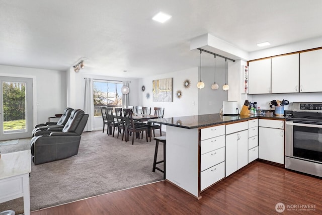 kitchen featuring a peninsula, white cabinetry, open floor plan, stainless steel electric range oven, and dark countertops