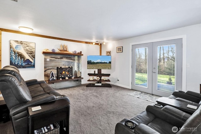 carpeted living area featuring a warm lit fireplace, baseboards, and french doors