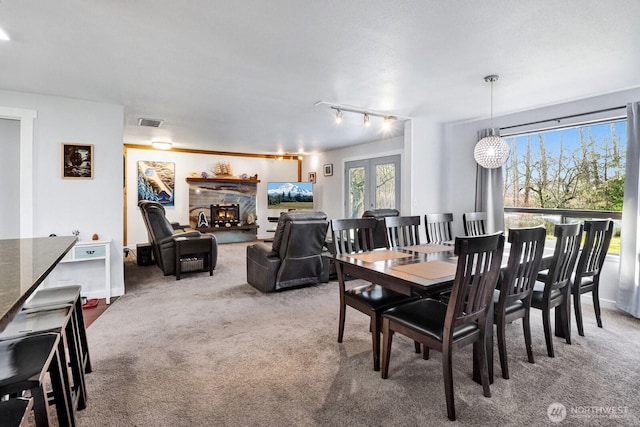 carpeted dining area with french doors, visible vents, and a fireplace