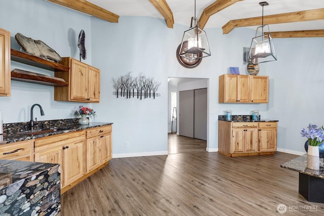 kitchen featuring baseboards, dark stone countertops, wood finished floors, open shelves, and a sink