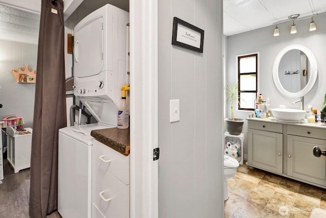 laundry room with laundry area, a sink, and stacked washer / drying machine