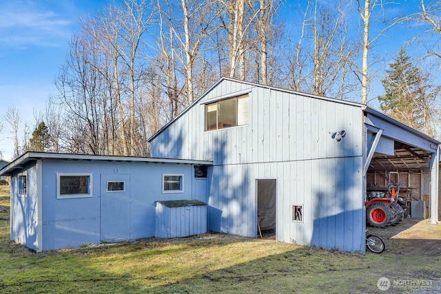 view of property exterior featuring a carport, an outbuilding, a yard, and driveway