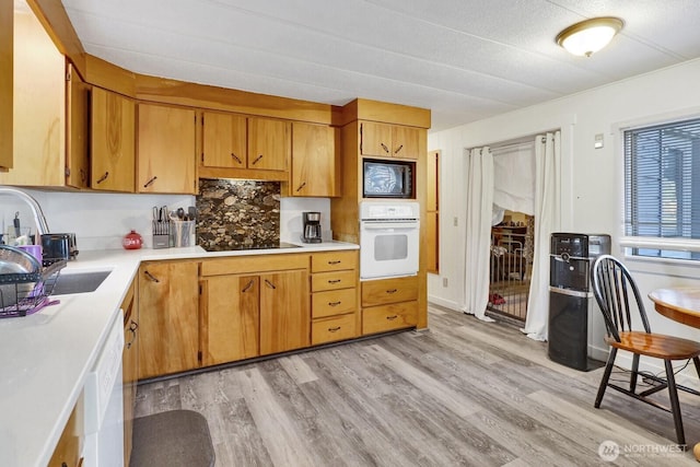 kitchen with black appliances, light countertops, light wood-style floors, and brown cabinetry