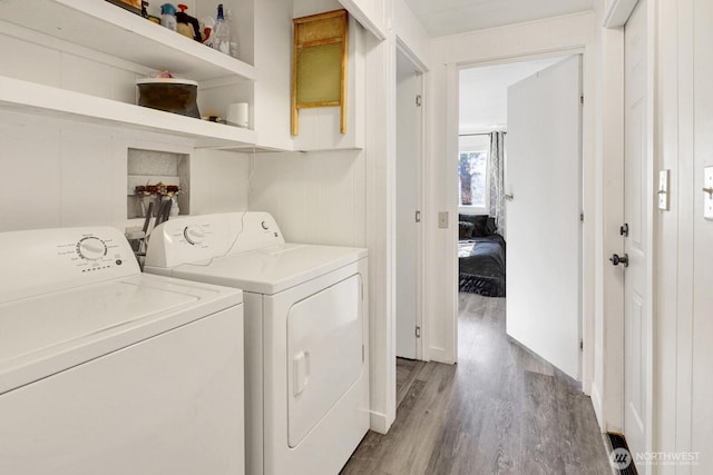 washroom featuring laundry area, wood finished floors, and washing machine and dryer